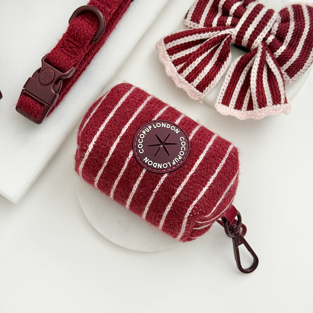Knitted dog poop bag dispenser with burgundy and baby pink vertical stripes and a colour matched zip closure.
