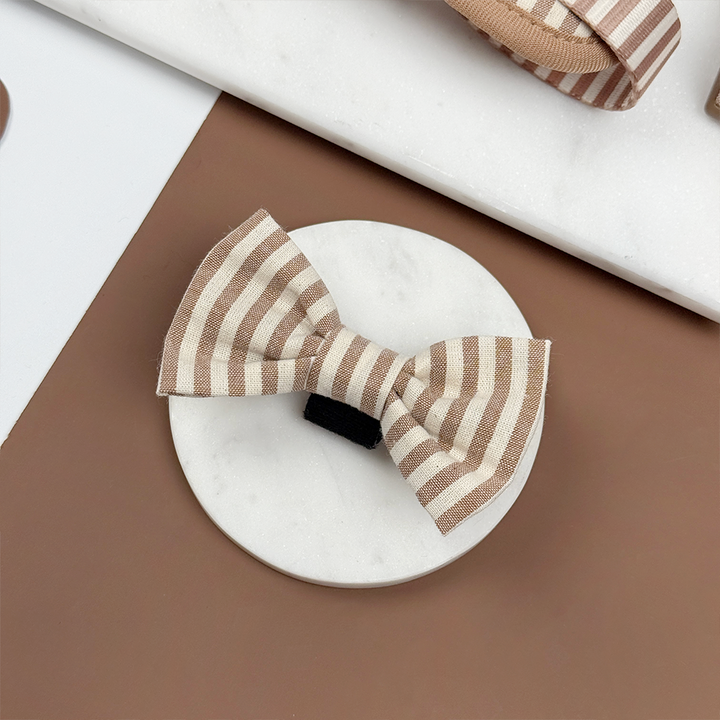 Brown and beige striped dog bow tie on a brown background.