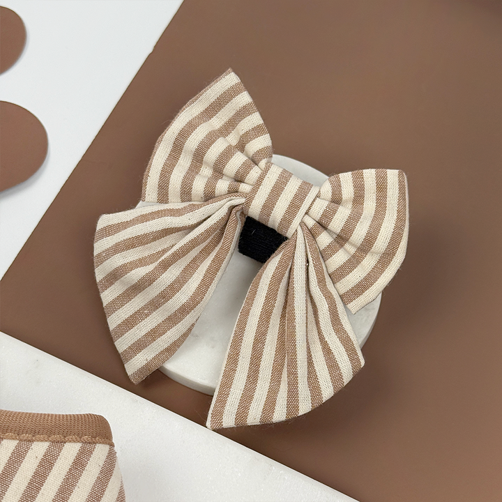Brown and beige striped dog sailor bow tie on a brown background.