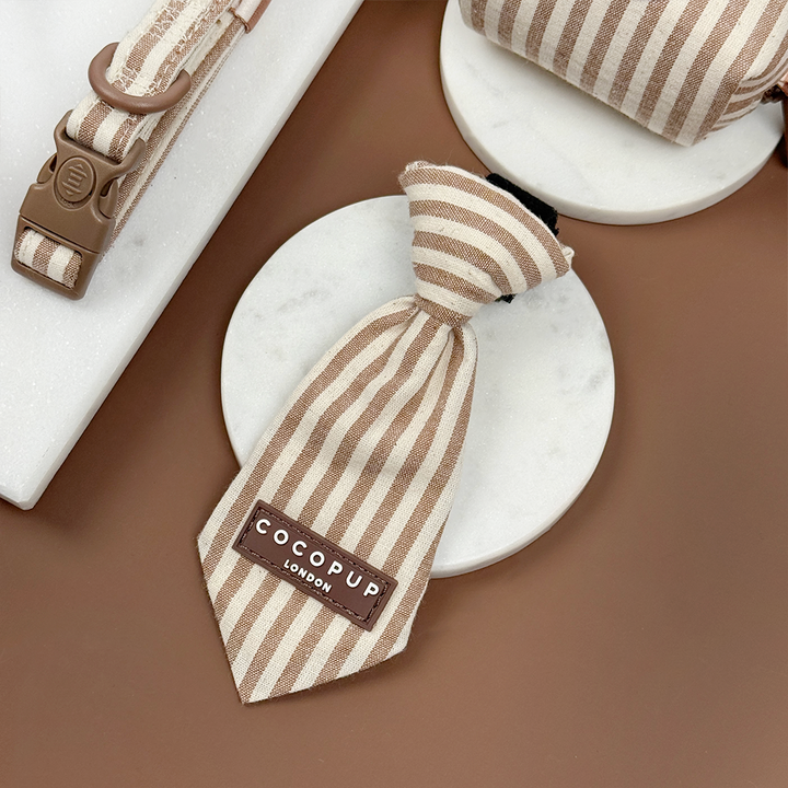Brown and beige striped dog tie with 'Cocopup London' logo on a brown bakground.