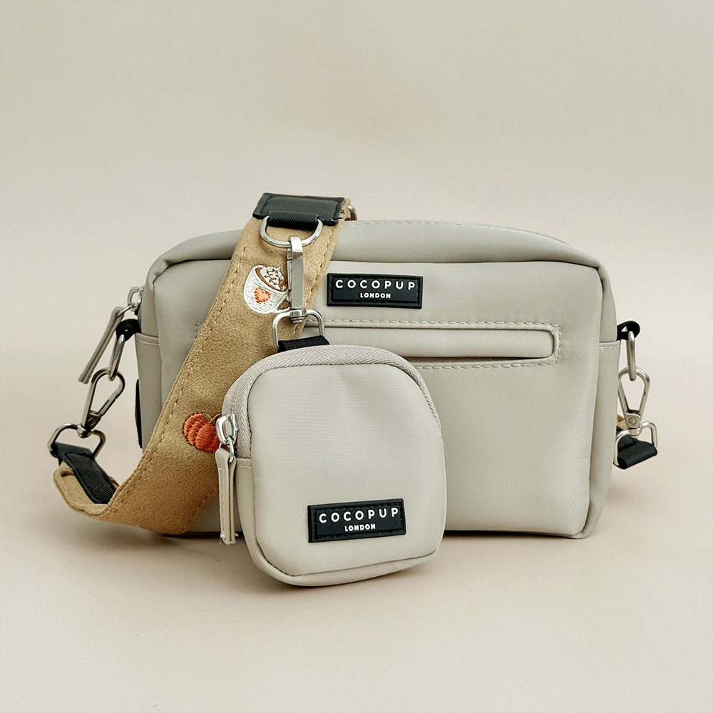 Beige Cocopup London crossbody bag with a smaller treat pouch attached, brown suede effect shoulder strap with black hardware with embroidered autumnal decals - pumpkins, chot chocolate, leaves. 