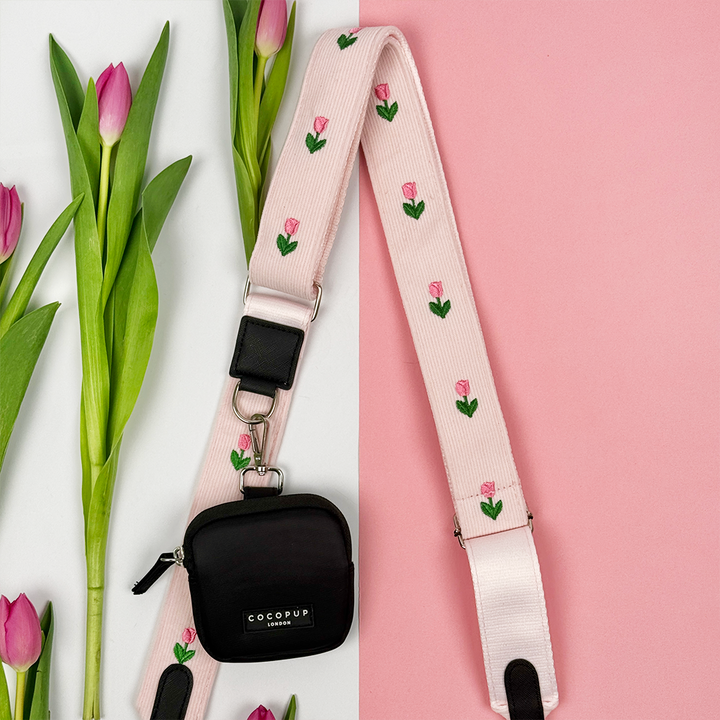 Black treat pouch attached to pink tulip bag strap on a pink and white background.